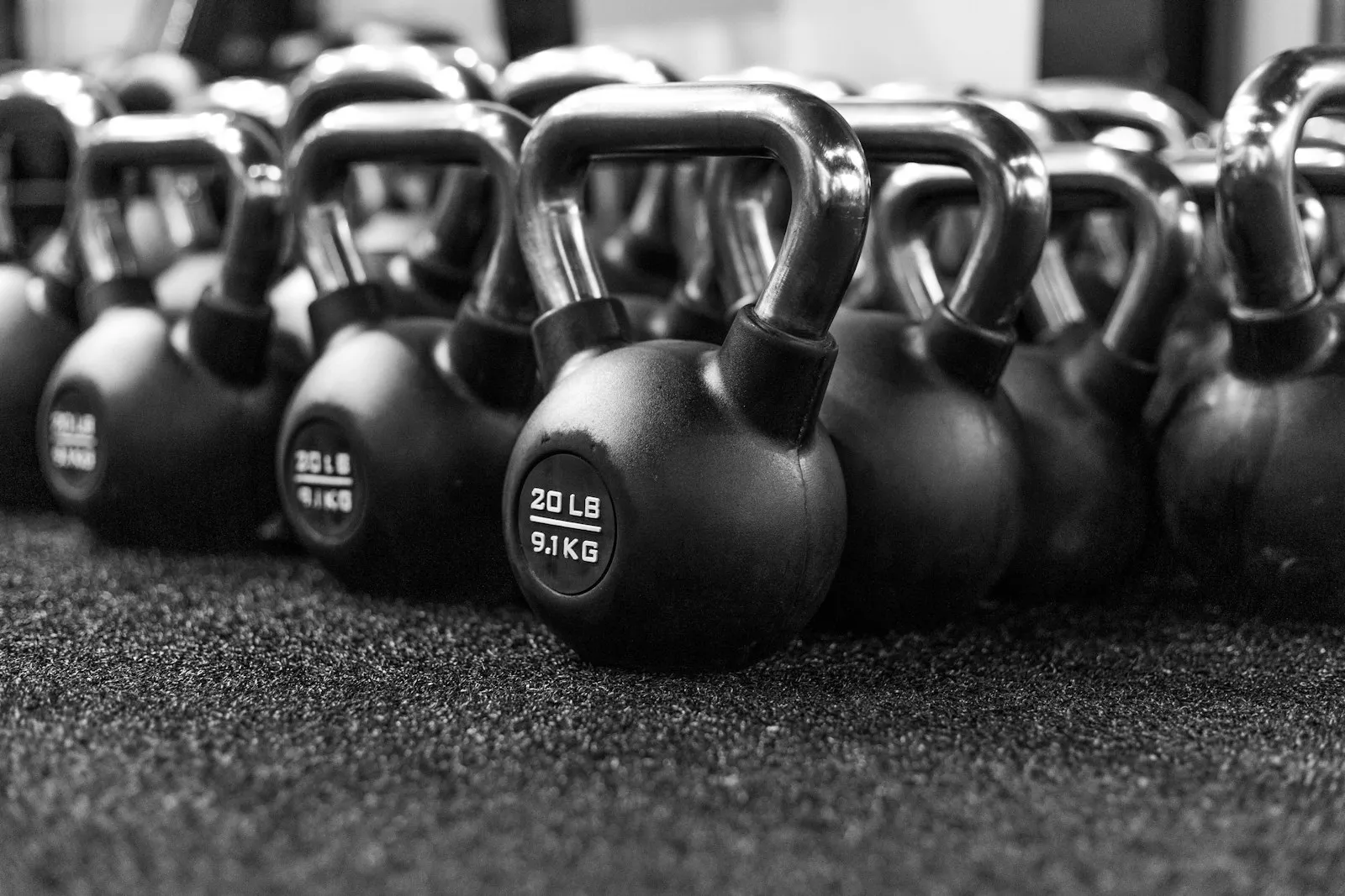 Kettlebells lined up on a rubber gym floor