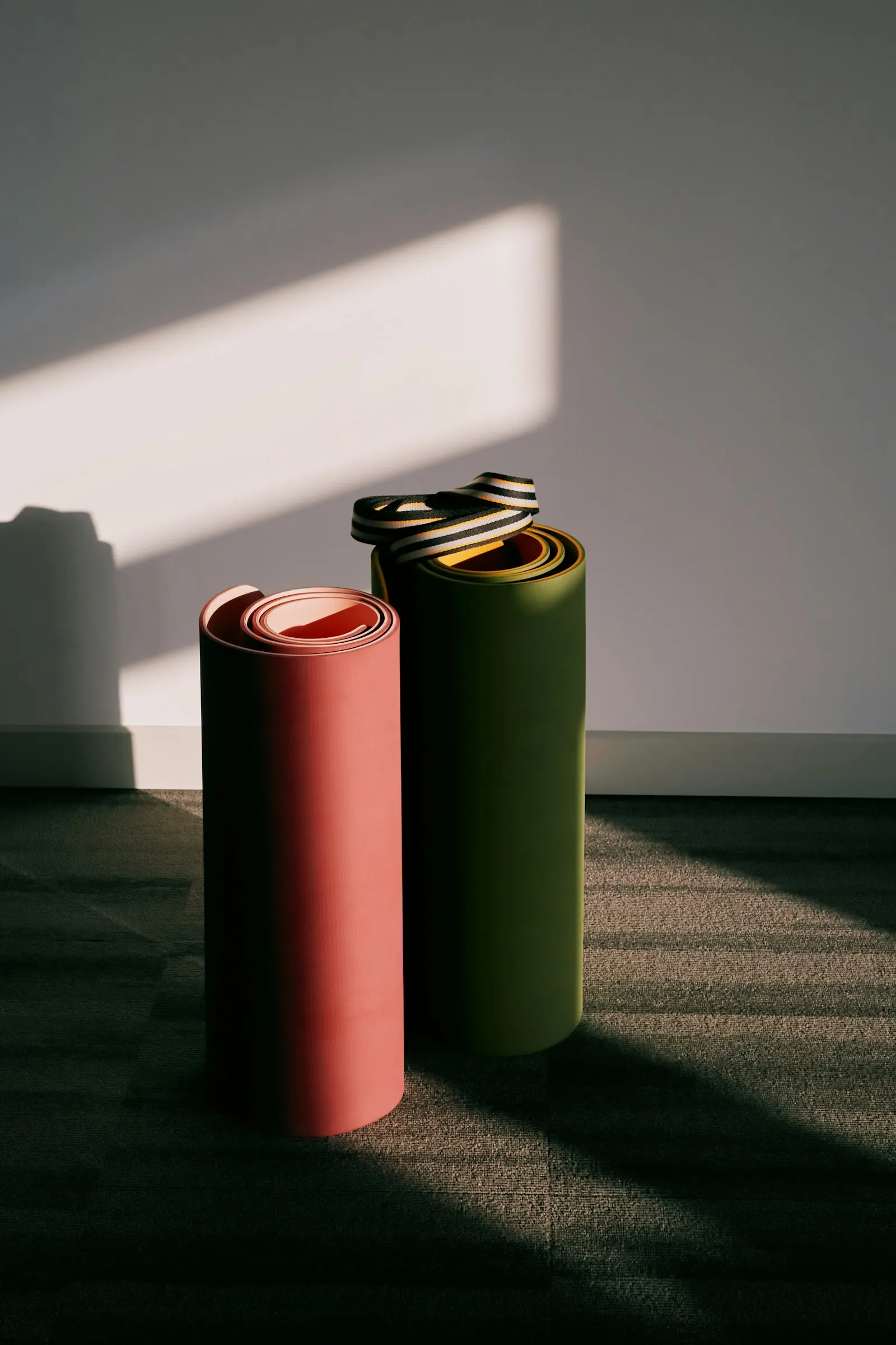 Two rolled exercise mats standing against a wall