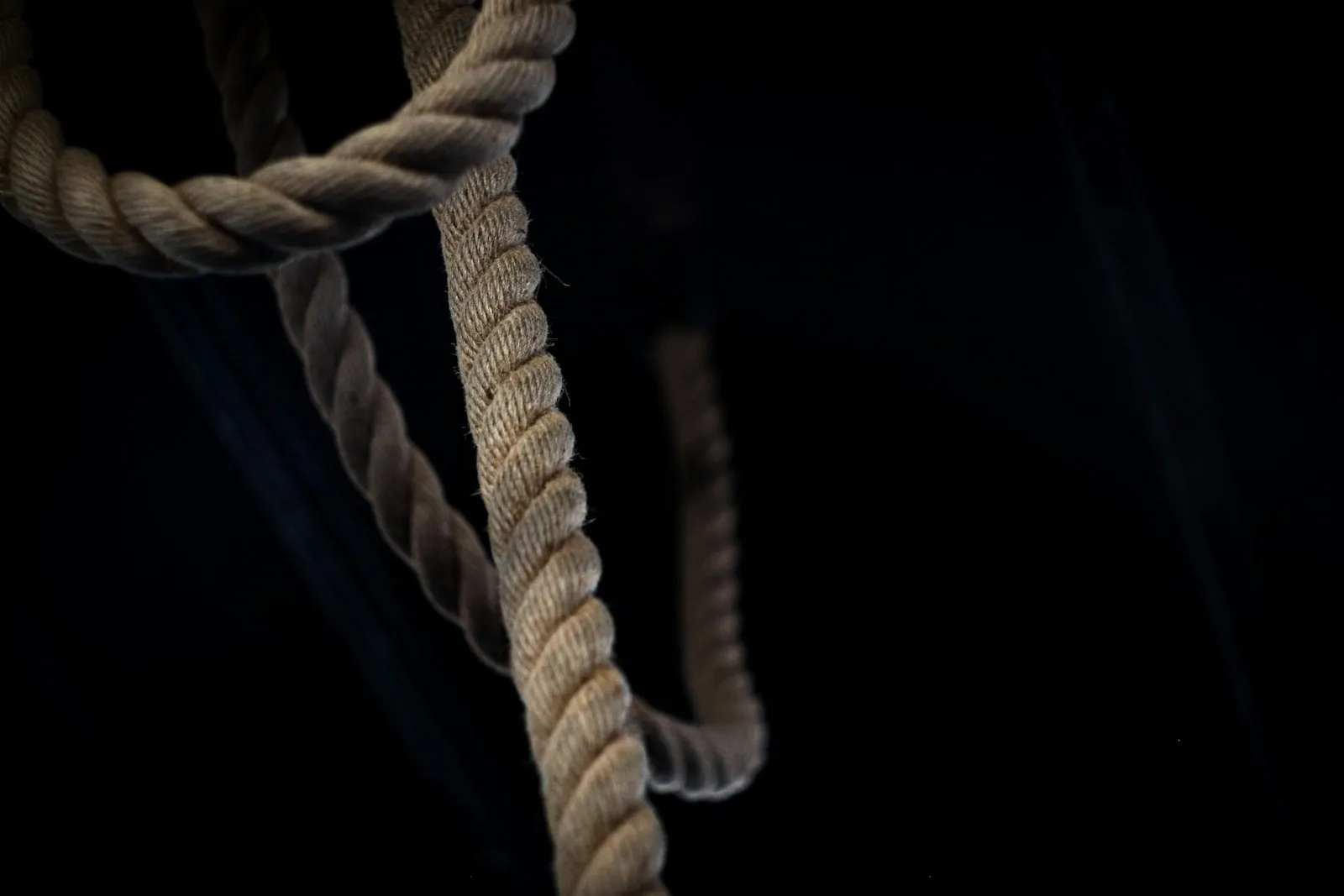 A heavy rope hanging against a black background